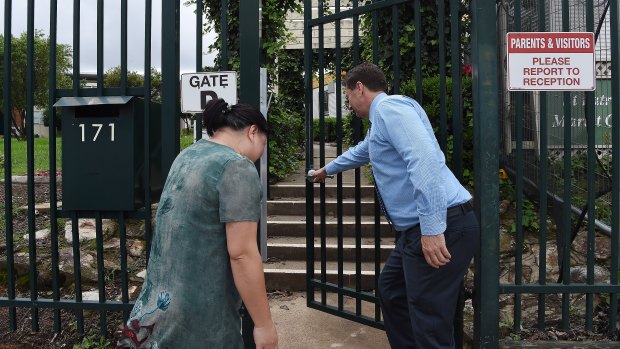 The deputy principal of St Patrick’s Marist College in Dundas, Sydney opens the gate to a parent of a student. Two students from the school were diagnosed with COVID-19 on Monday.