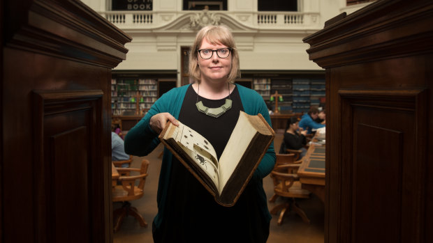 Rare book historian Dr Anna Welch with one the books that had images cut out of it. 