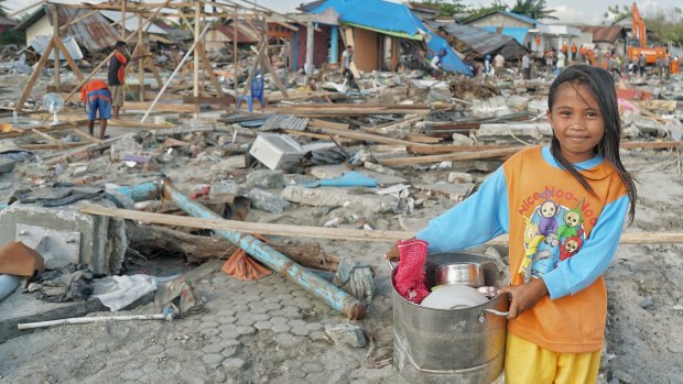 Ten-year-old Suci Rahmadi at Mamboro beach with pots and pans  she has collected from the debris. 