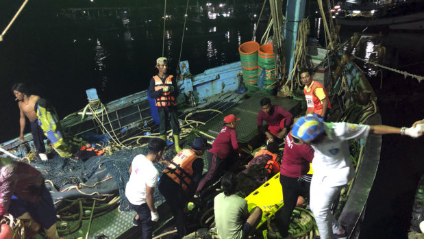 Rescued tourists from a boat that sank are helped onto a pier from a fishing boat in Phuket.