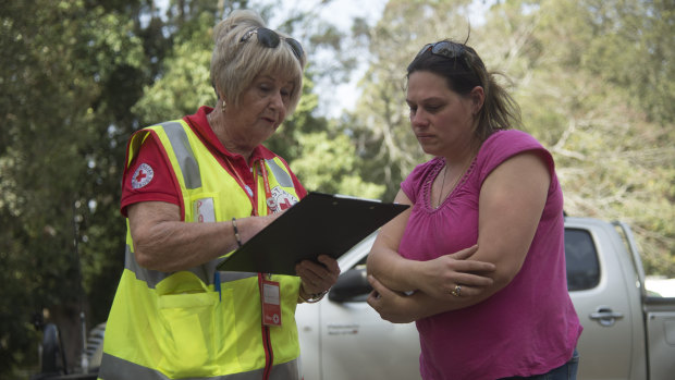 Courier driver Sophie Bryden (right), 38, speaks to Red Cross workers at Canungra Sports and Recreation Ground.
