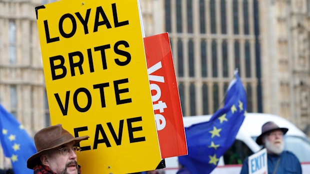 A vote leave pro-Brexit demonstrator holds a placard with anti Brexit protesters in the background as they voice their opinions outside the Palace of Westminster, in London.