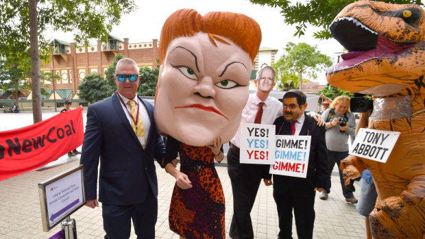 Protestors wearing masks depicting One Nation leader Pauline Hanson, Prime Minister Malcolm Turnbull and Gautam Adani with a person in a dinosaur costume depicting former Prime Minister Tony Abbott