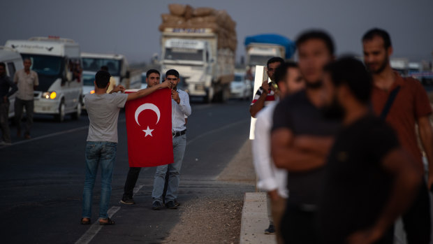 People wave Turkish flags in support of Turkish soldiers crossing the border into Syria.