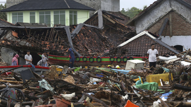 People inspect the damage at a tsunami-ravaged village in Sumur, Indonesia, on Christmas Day.