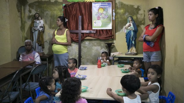 Children eat at a soup kitchen as adults wait to be served in the Petare slum, in Caracas, Venezuela, last week.