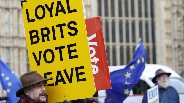 A vote leave pro-Brexit demonstrator holds a placard with anti Brexit protesters in the background as they voice their opinions outside the Palace of Westminster, in London.