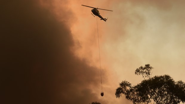 A helicopter circles overhead near Yanderra Road as the Green Wattle Creek Fire approaches Yanderra. 