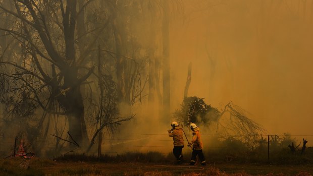 NSW RFS fire fighters surrounded by smoke as they work on battling a fire at Tahmoor, NSW. 