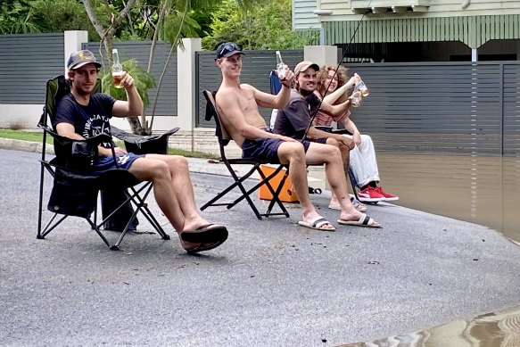 Tom and and a group of mates wait for the water to recede from his flooded house at William Parade, Yeronga.