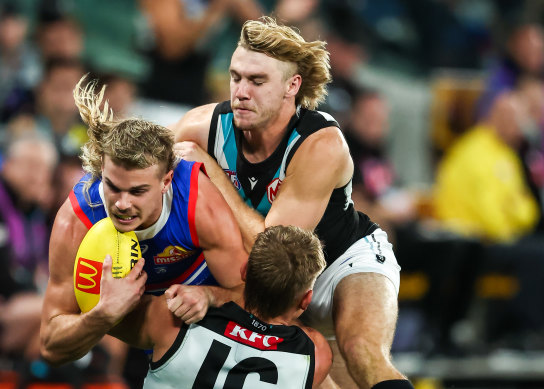 Bailey Smith of the Bulldogs is tackled by Ollie Wines and Jason Horne-Francis of the Power.