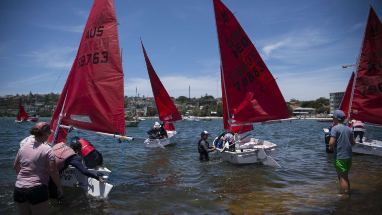 Mirror Dinghy class sailing boats launch before a race on Sydney Harbour. 