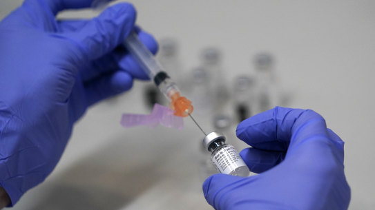 A pharmacy technician loads a syringe with Pfizer’s COVID-19 vaccine.