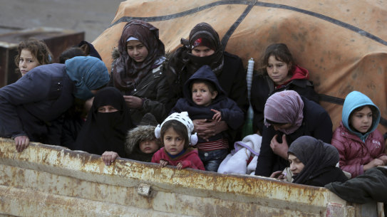 Syrians sit in the back of a truck as they flee the advance of the government forces in the province of Idlib, Syria. 