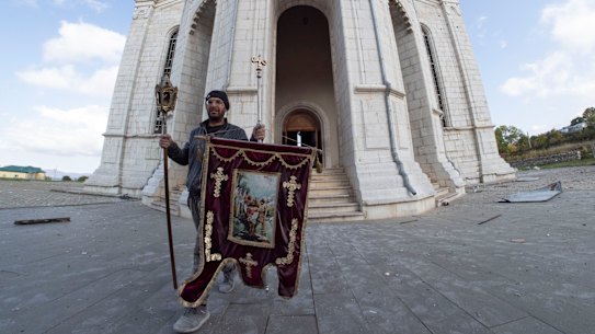 A man carries out a banner from the Holy Saviour Cathedral damaged by shelling during a military conflict, in Shushi, in the self-proclaimed Republic of Nagorno-Karabakh.