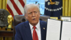 President Donald Trump holds up a signed executive order in the Oval Office of the White House.
