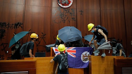 Protesters erect a Hong Kong colonial flag and deface the Hong Kong logo at the Legislative Chamber.
