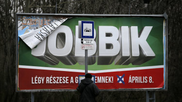 A man waits on the tram station by a billboard for the nationalist Jobbik party, reading: ''Participate in victory - April 8.'' in Budapest, Hungary. 