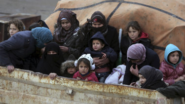 Syrians sit in the back of a truck as they flee the advance of the government forces in the province of Idlib, Syria. 