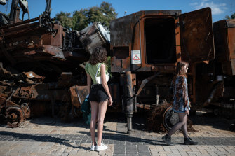 Las mujeres jóvenes caminan junto a los vehículos militares rusos quemados que se exhiben en la Plaza de San Miguel el 28 de julio en Kyiv.