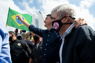 Brazilian President Jair Bolsonaro, centre, with Minister of Institutional Security and Brazilian Army General Augusto Heleno waves to supporters.