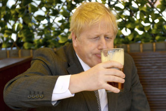 Premierul britanic Boris Johnson sorbind o bere.