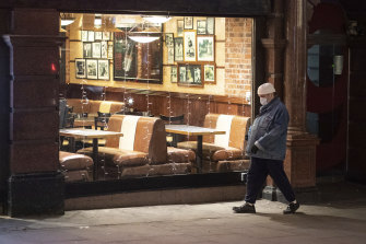 A pedestrian walks past an empty restaurant in central London. European countries are also cutting their isolation times for those infected or exposed to COVID.