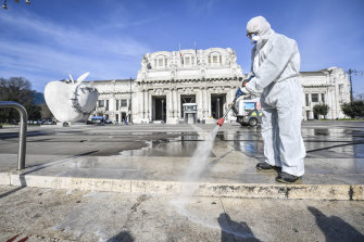 A worker wearing a protective suit disinfects the area in front of Milano Centrale, which is usually the bustling traffic centre of the country's business capital of Milan. 