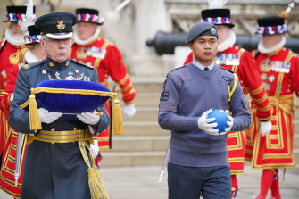 Un membre des cadets de l'air de la Royal Air Force, à droite, tenant le Globe du Commonwealth des Nations à son arrivée à la Tour de Londres.  Le ballon sera utilisé pour éclairer le phare principal du palais de Buckingham.