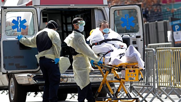 A patient is wheeled out of Elmhurst Hospital Center to a waiting ambulance.
