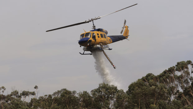 A helicopter water bombs a bushfire at Northmead on Sunday.