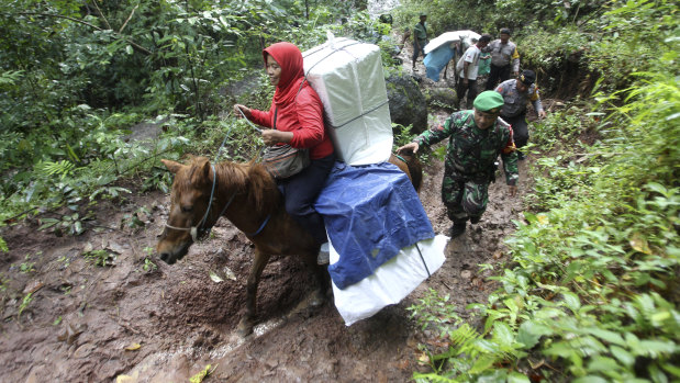 Officers escort electoral workers using horses to distribute ballot boxes and other election paraphernalia to polling stations in remote villages in Tempurejo, East Java, Indonesia.