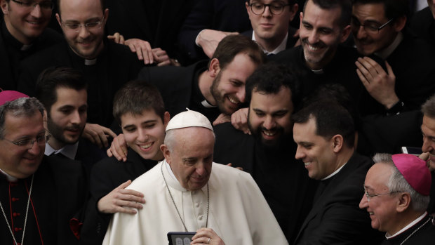 Pope Francis poses for a photo with a group of priests at the end of his weekly general audience on Wednesday.