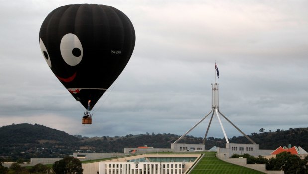 The Black Magic hot air balloon, also known as "Golly", is seen flying over Parliament House during the 2011 Canberra Balloon Spectacular.