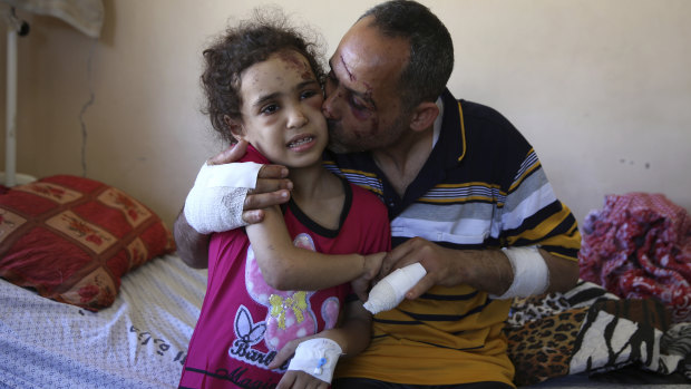 Riad Ishkontana embraces his daughter Suzy, 7, the only one of his children to survive an air strike on Sunday on the Gaza building in which the family lived. His wife was also killed. 