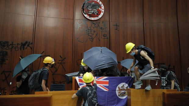 Protesters erect a Hong Kong colonial flag and deface the Hong Kong logo at the Legislative Chamber.