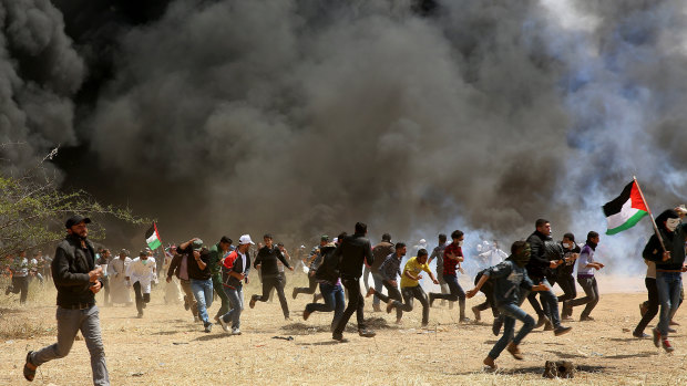 Protesters run for cover from teargas and live bullets fired by Israeli soldiers on Friday during clashes at the Gaza's border with Israel near Khan Younis.