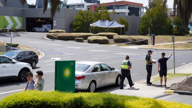 A woman's body lies under a tent as police question potential witnesses in Bundoora.