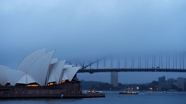 Fog and rain hang over the Opera House and Harbour Bridge.
