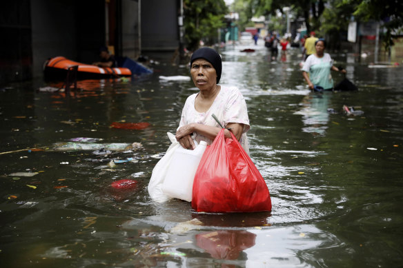 A woman wades through flood water in Jakarta after monsoons.