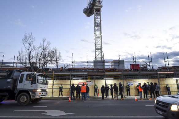 Police line up outside the Toorak Road worksite as CFMEU members gather on July 1,