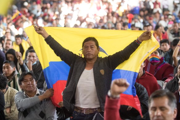 An indigenpus man holds a Ecuadorian flag  during a general assembly called by indigenous groups to mourn the rests of two people who died in the protests against the economic measures taken by President of Ecuador Lenin Moreno. 