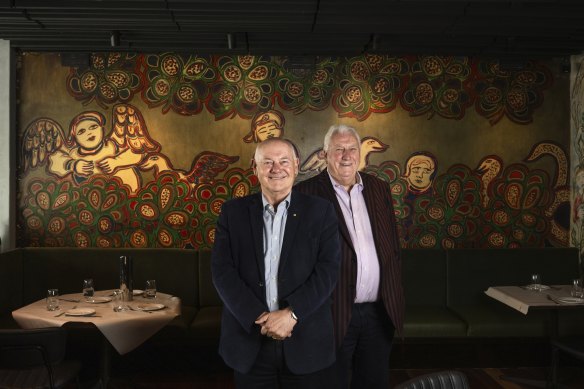 Tolarno Hotel owners Bernard Corser and James Fagan in front of a historic Mirka Mora mural in the hotel’s restaurant. 