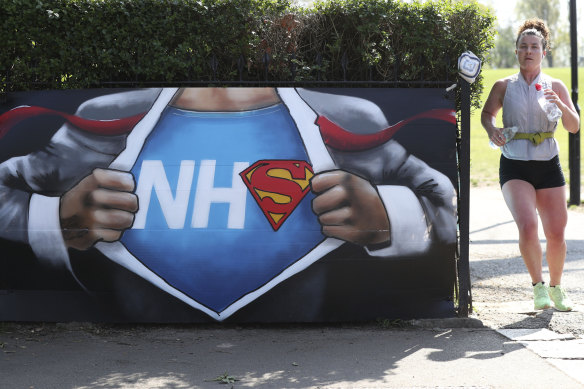 A runner passes street art in appreciation of the NHS placed near to the Francis Drake Bowls Club in Hilly Fields Park, in Lewisham, London.