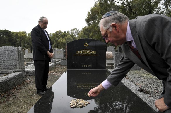 Dunera Association president Ron Reichwald places a stone on Kurt Kriszhaber’s new tombstone in Fawkner cemetery, after Michael Cohen (left) said prayers.