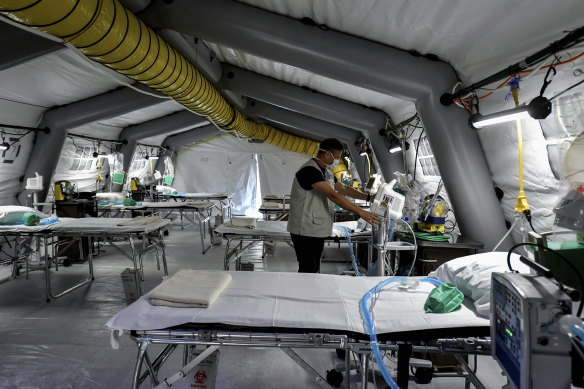 A staffer checks equipment set up in a temporary field hospital that is about to accept coronavirus patients.