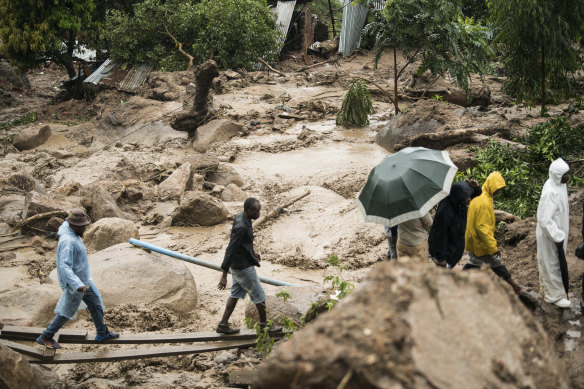 People cross a raging river in Blantyre, Malawi.