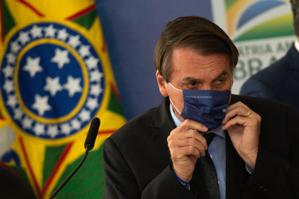 President of Brazil Jair Bolsonaro puts a face mask last week, a rare use of the mask for the leader who has mocked their use.