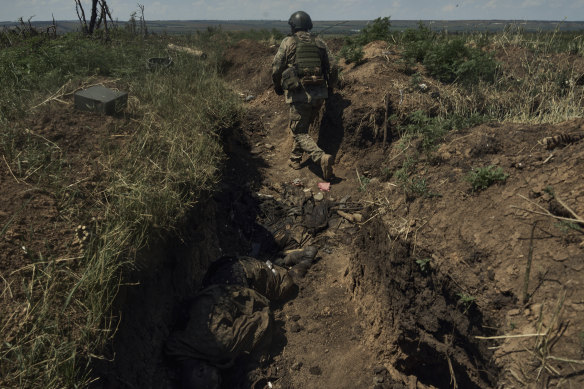 A Ukrainian soldier in a recently captured Russian trench with deceased Russian soldiers, on the frontline near Bakhmut, Donetsk region.
