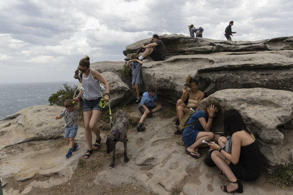 People at Bondi take cover as a southerly buster ambushes walkers with gusts of sand and dust.